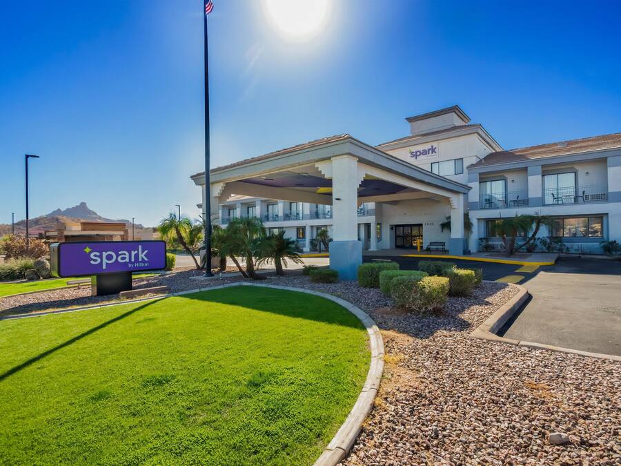 Un hotel con cielo despejado, un letrero que dice 'Spark by Hilton' y un césped bien cuidado.