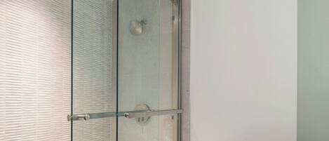 A modern bathroom with a glass-enclosed shower, a white toilet, and a tiled floor.