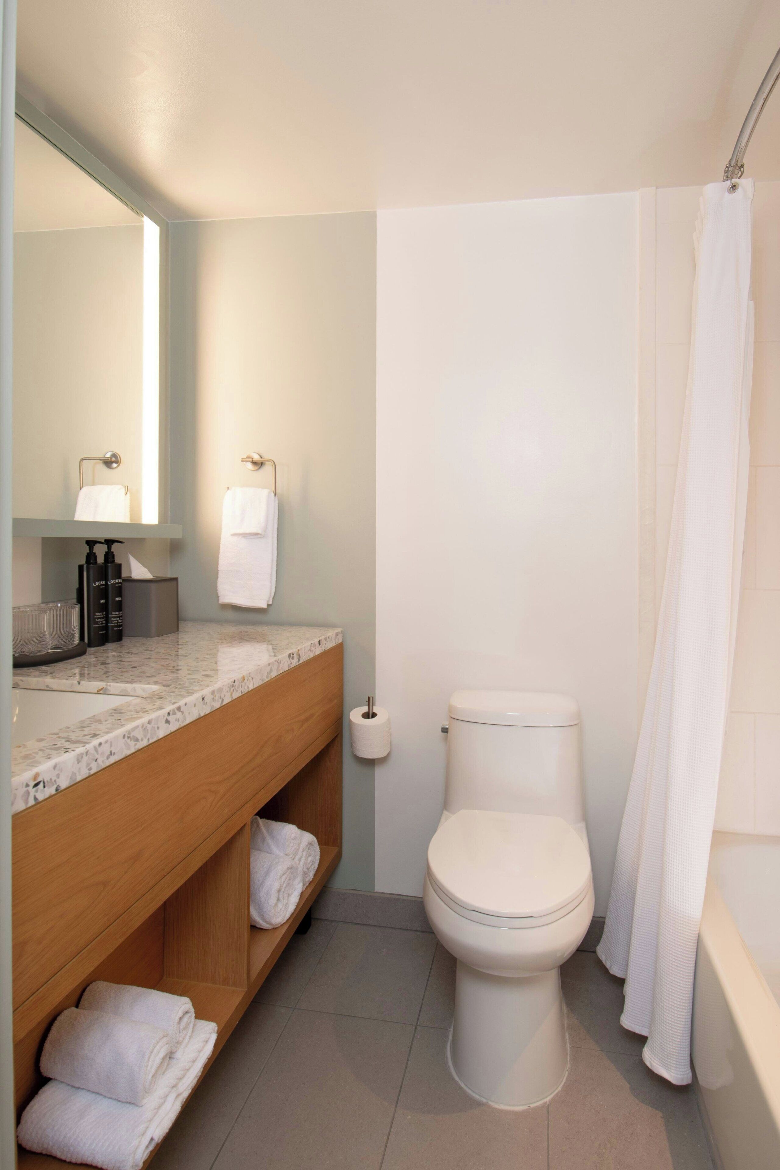 Un baño con inodoro, lavamanos y cortina de ducha.
