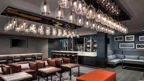 A modern bar area with multiple seating options, including leather booths and tables, and a bar counter with a variety of bottles. - Marin Hilltop Hotel (San Rafael)