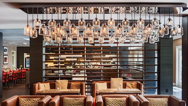 A restaurant with leather booths, wooden tables, and hanging light fixtures. - Marin Hilltop Hotel (San Rafael)