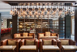 A restaurant with leather booths, wooden tables, and hanging light fixtures. - Marin Hilltop Hotel (San Rafael)