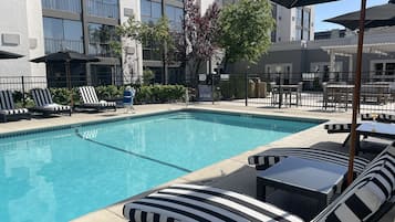 Alberca al aire libre, sombrillas en la alberca y camastros