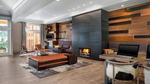 A modern living room with a fireplace, a sofa, a coffee table, and a desk with a computer. - Marin Hilltop Hotel (San Rafael)