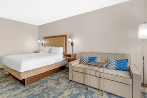 A hotel room with a bed, a sofa, a nightstand, and two wall-mounted lamps. - Hampton Inn & Suites Atlanta/Duluth/Gwinnett County (Duluth)