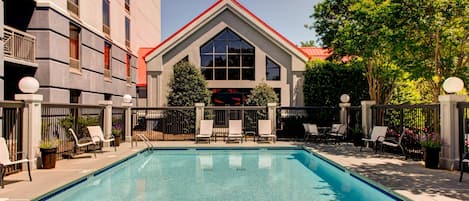 Een buitenzwembad, ligstoelen bij het zwembad