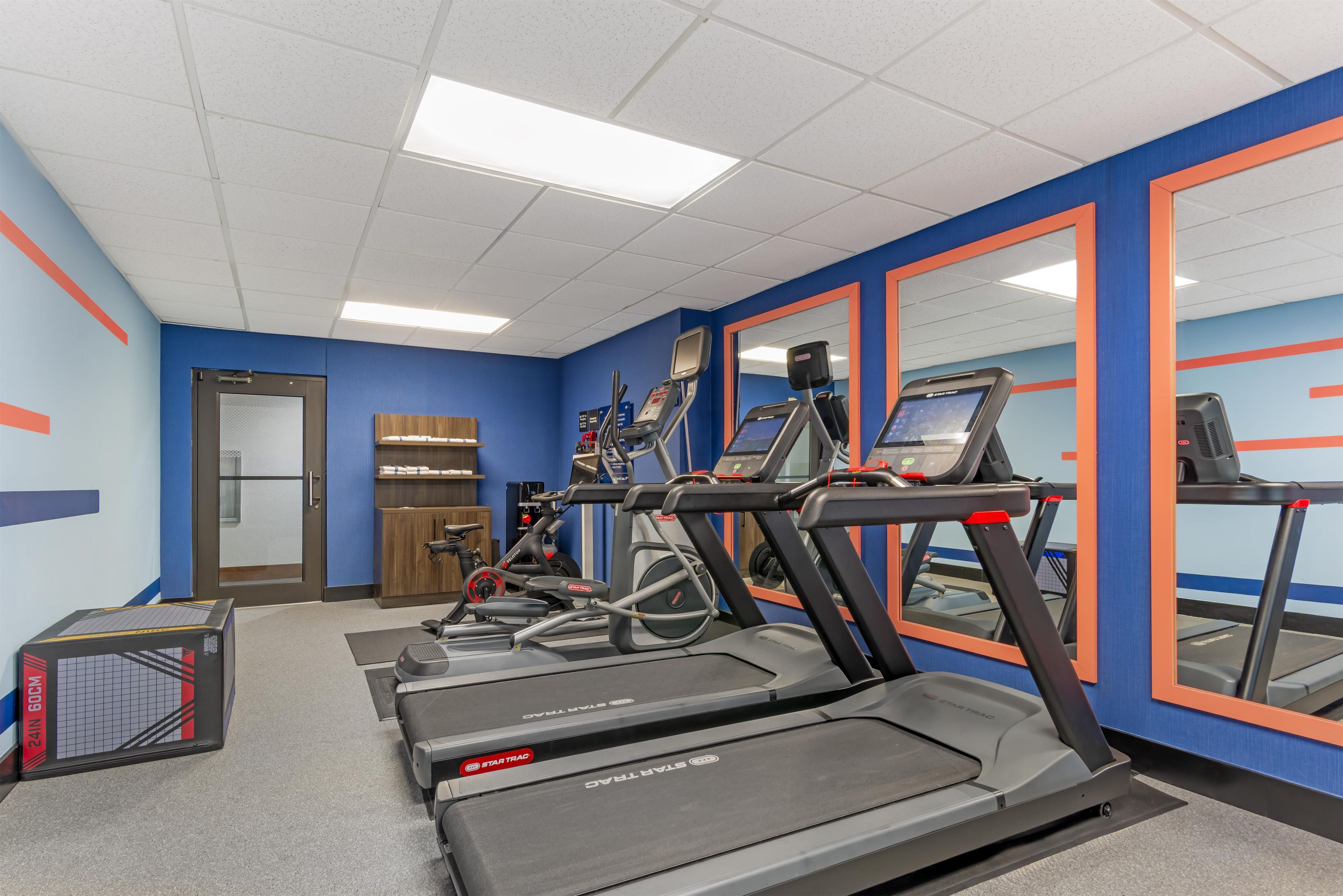 A gym with treadmills, a weight bench, and a mirror.