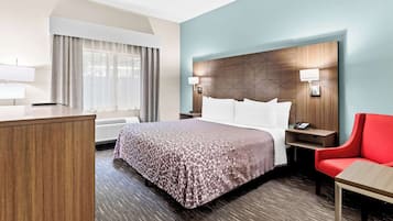 Une chambre d’hôtel avec un lit, un bureau, une chaise et une table de chevet.
