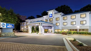 A hotel with a modern design, featuring a prominent Best Western sign, a covered entrance, and a well-lit facade.