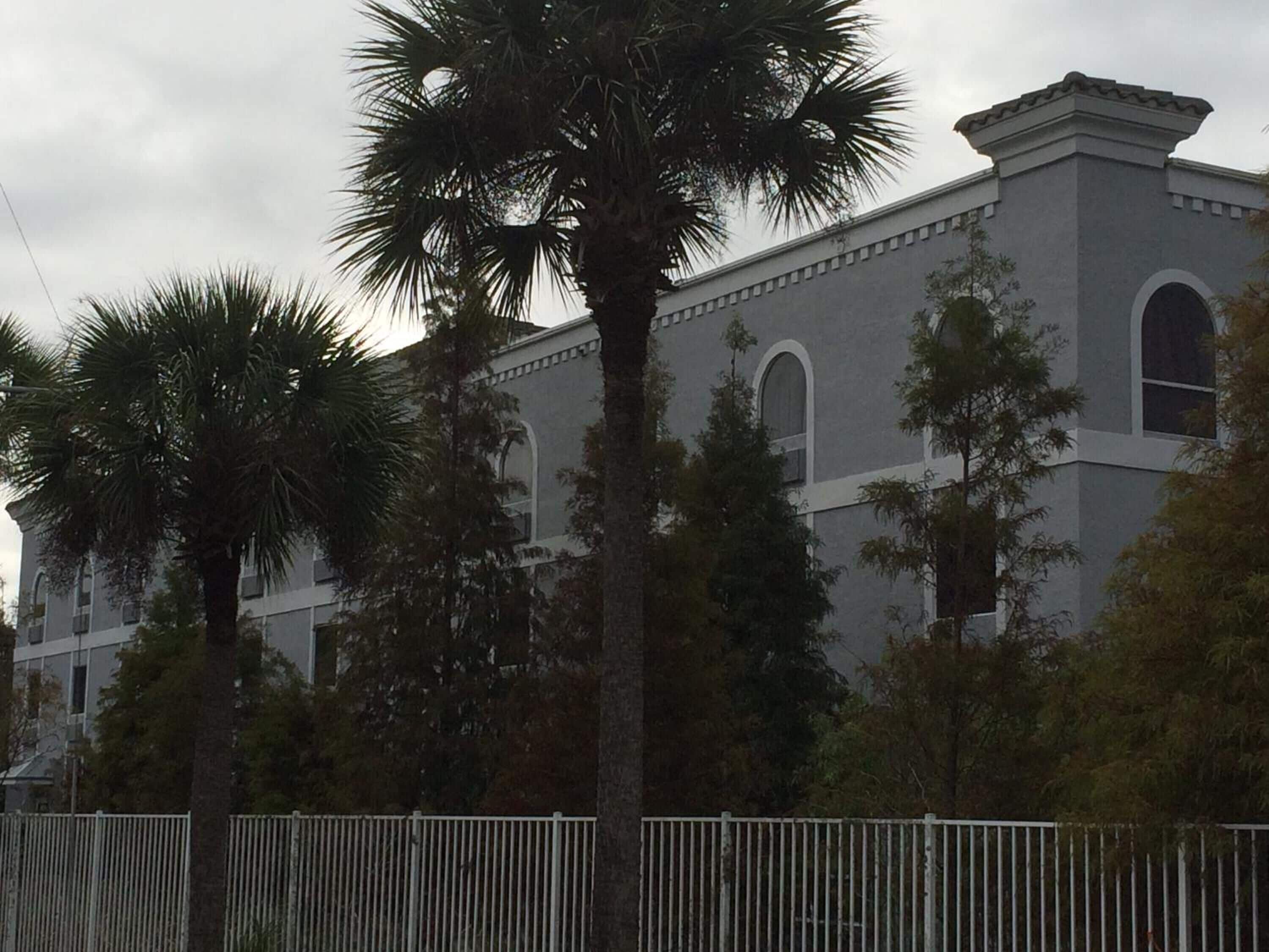 A building with a grey facade, arched windows, and a flat roof.