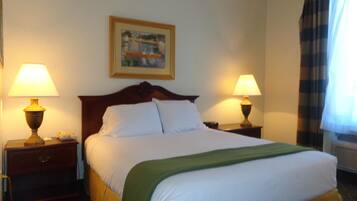 Habitación de hotel con una cama grande, dos lámparas de noche, un cuadro en la pared y una ventana con cortinas.
