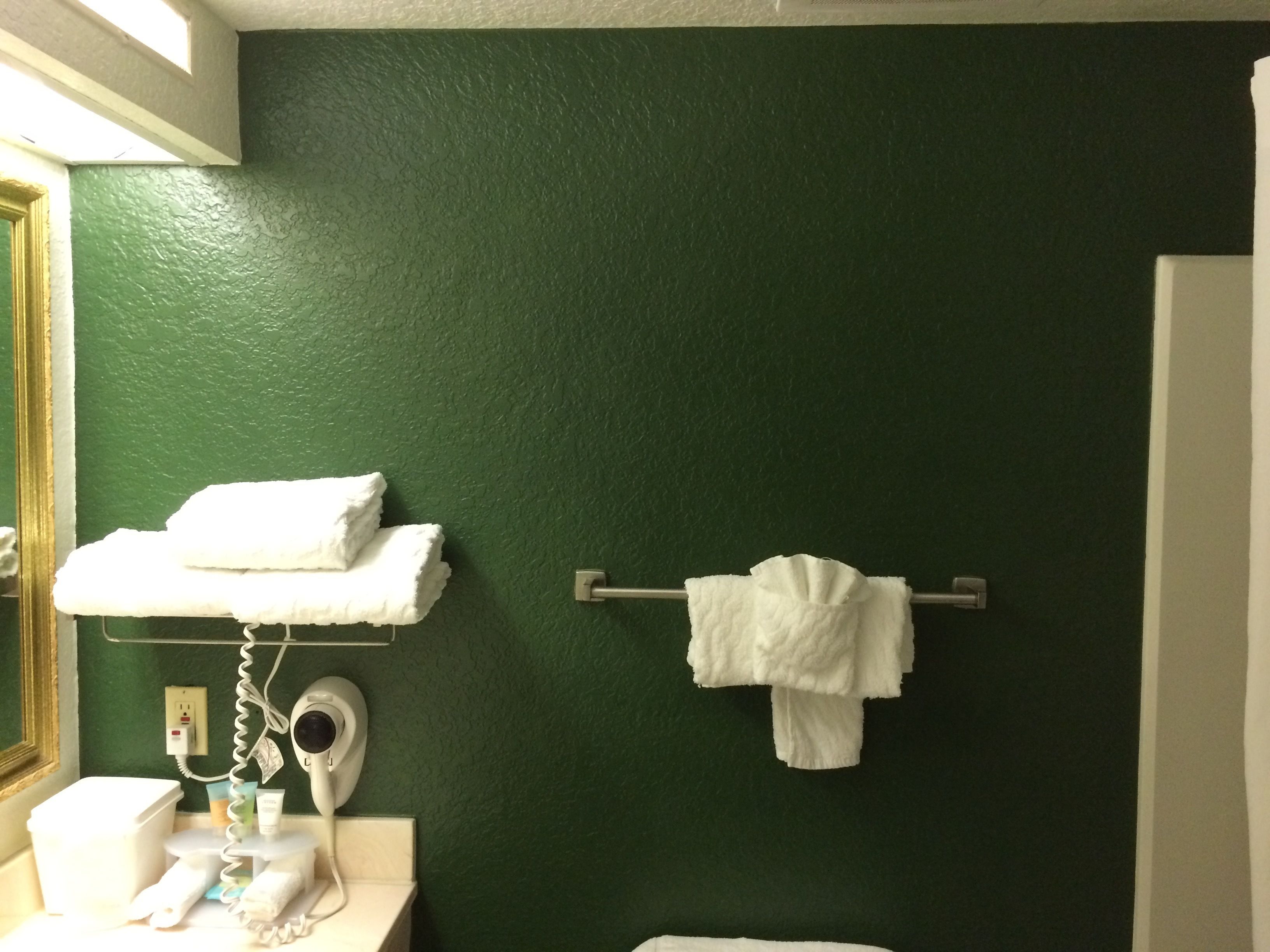 Un baño con paredes verdes, un lavamanos blanco y un perchero para toallas.