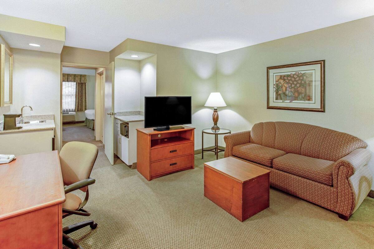 A hotel room with a sofa, a TV, a desk, and a lamp.