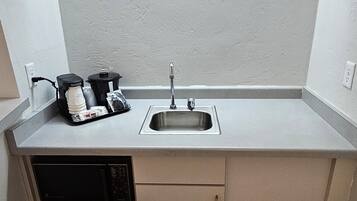 A compact kitchenette with a sink, a dishwashing unit, and a coffee maker.