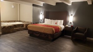 A modern hotel room with a large bed, a built-in bathtub, and a separate seating area. - Econo Lodge Donalsonville (Donalsonville)