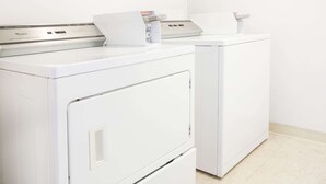 Two white front-loading washers in a laundry room with a tiled floor. - Days Inn by Wyndham Alma (Alma)