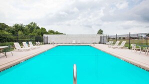 A rectangular swimming pool with a clear blue water surface, surrounded by white lounge chairs and a metal fence. - Days Inn by Wyndham Alma (Alma)