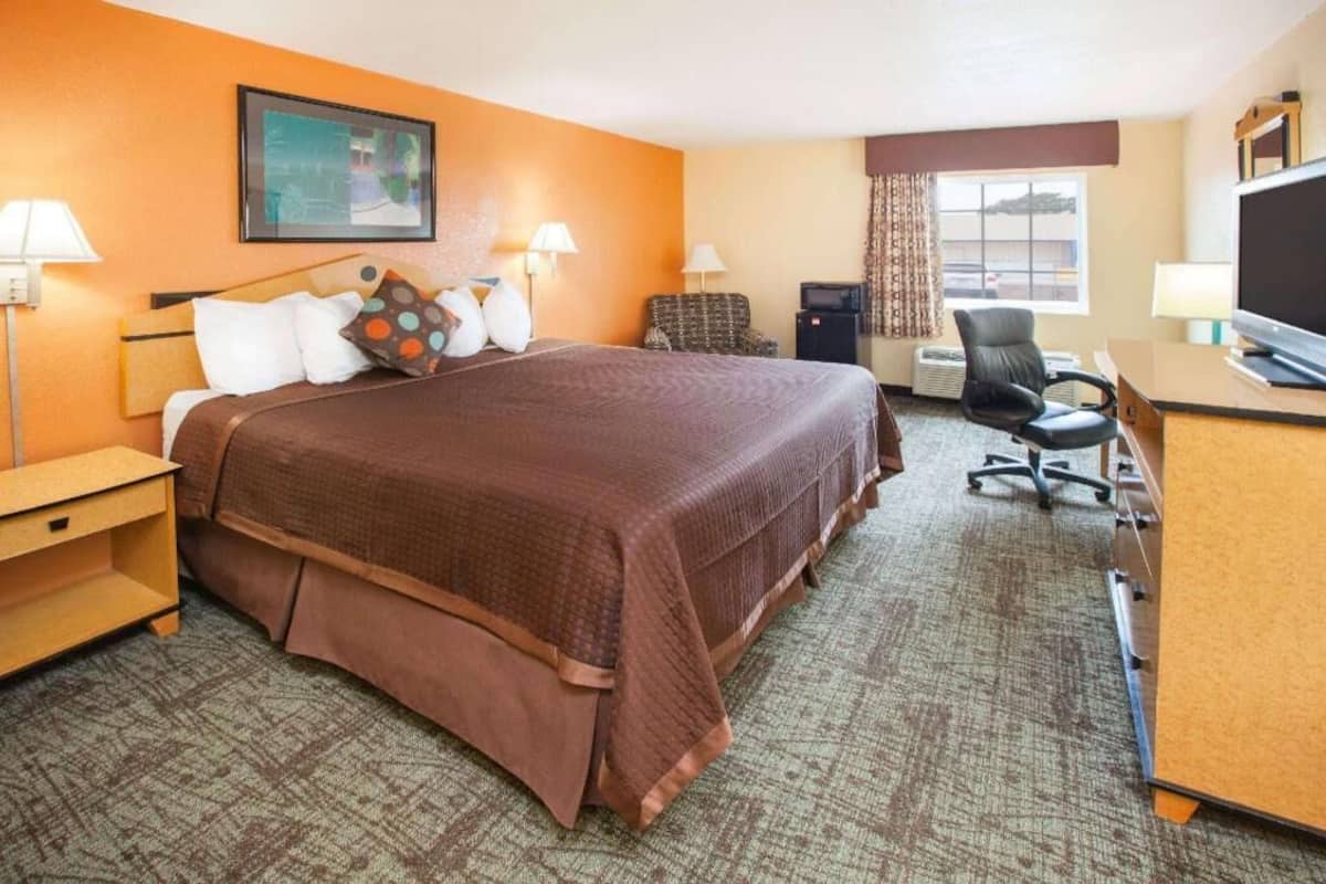 A hotel room with a large bed, a desk with a computer, a TV, and a chair.