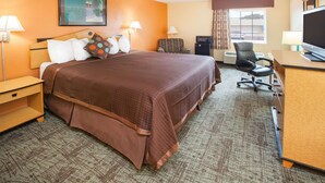 A hotel room with a large bed, a desk with a computer, a TV, and a chair. - Days Inn by Wyndham Alma (Alma)