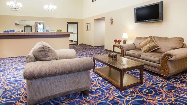 A hotel lobby with a reception desk, two sofas, a coffee table, and a TV mounted on the wall. - Days Inn by Wyndham Alma (Alma)