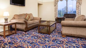 A living room with a sofa, armchair, coffee table, and a flat-screen TV mounted on the wall. - Days Inn by Wyndham Alma (Alma)