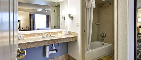 A bathroom with a sink, mirror, shower, and bathtub.