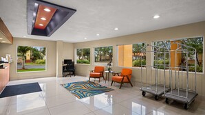 A hotel lobby with a reception desk, seating area, and large windows offering views of the outdoors. - Quality Inn - Near Serenoa Golf Club (Sarasota)