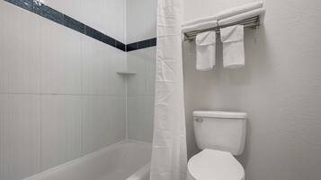 Un baño con bañera, inodoro y toallero.