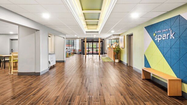 A modern interior with a wooden floor, a bench, and a wall with a geometric pattern and text. - Spark by Hilton Duluth (Duluth)