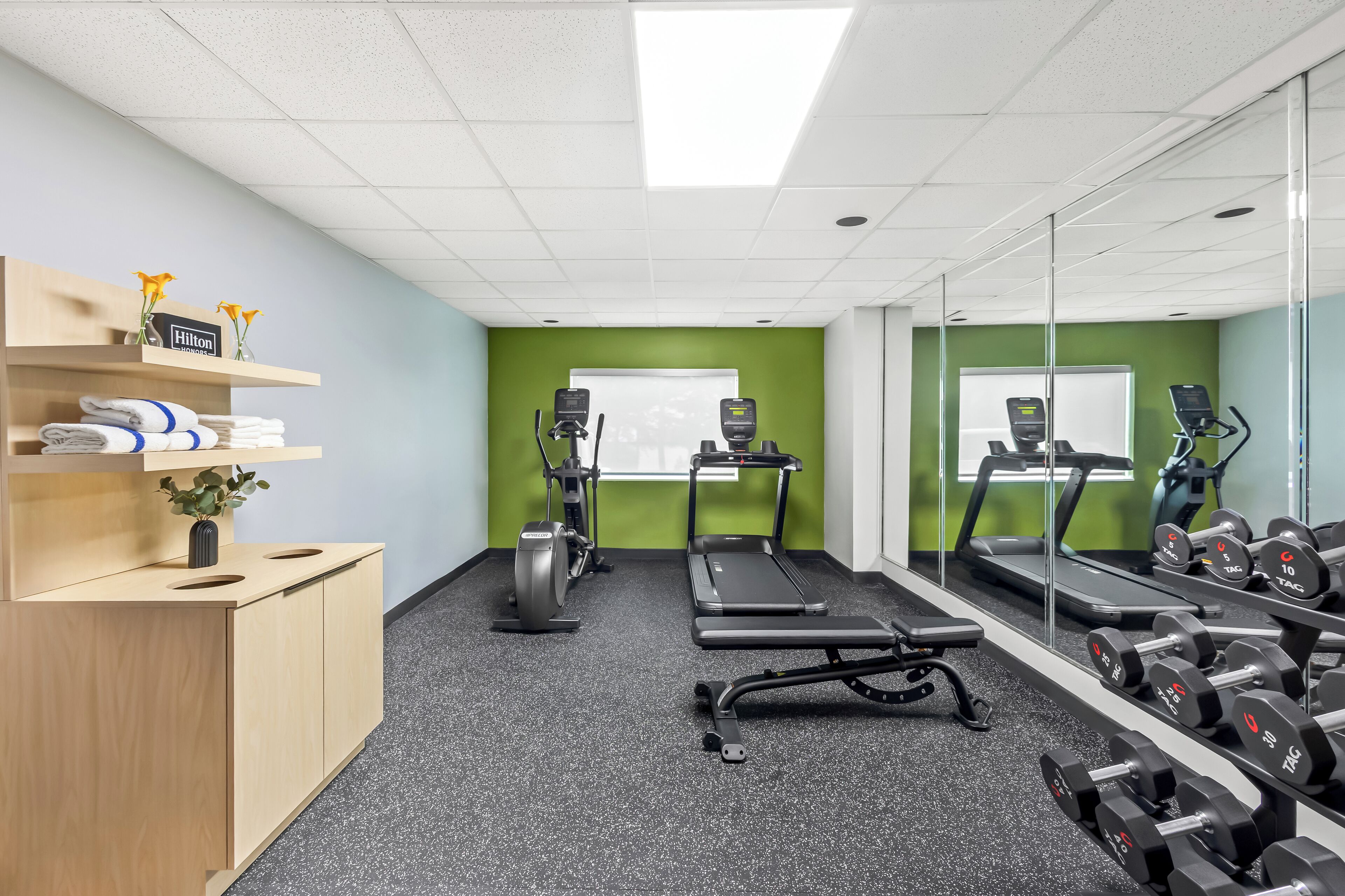 A gym with exercise equipment, a treadmill, and weights.