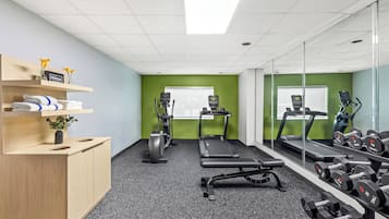 A gym with exercise equipment, a treadmill, and weights.