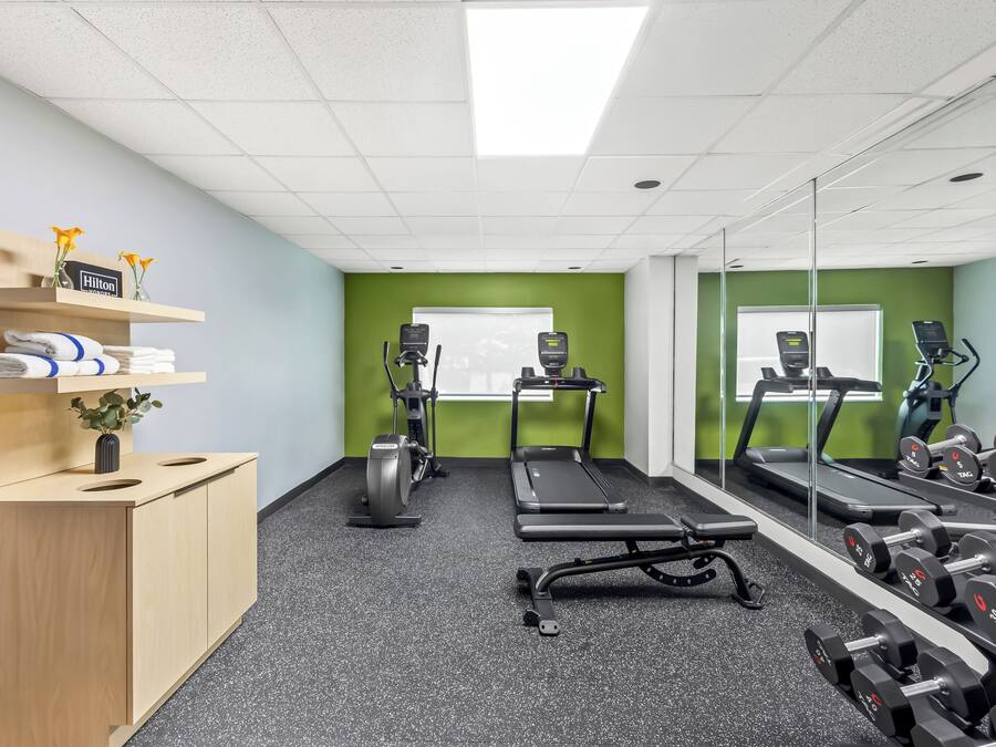 A gym with exercise equipment, a treadmill, and weights.
