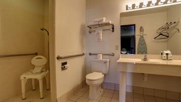 A bathroom with a toilet, a sink, a mirror, and a shower area.