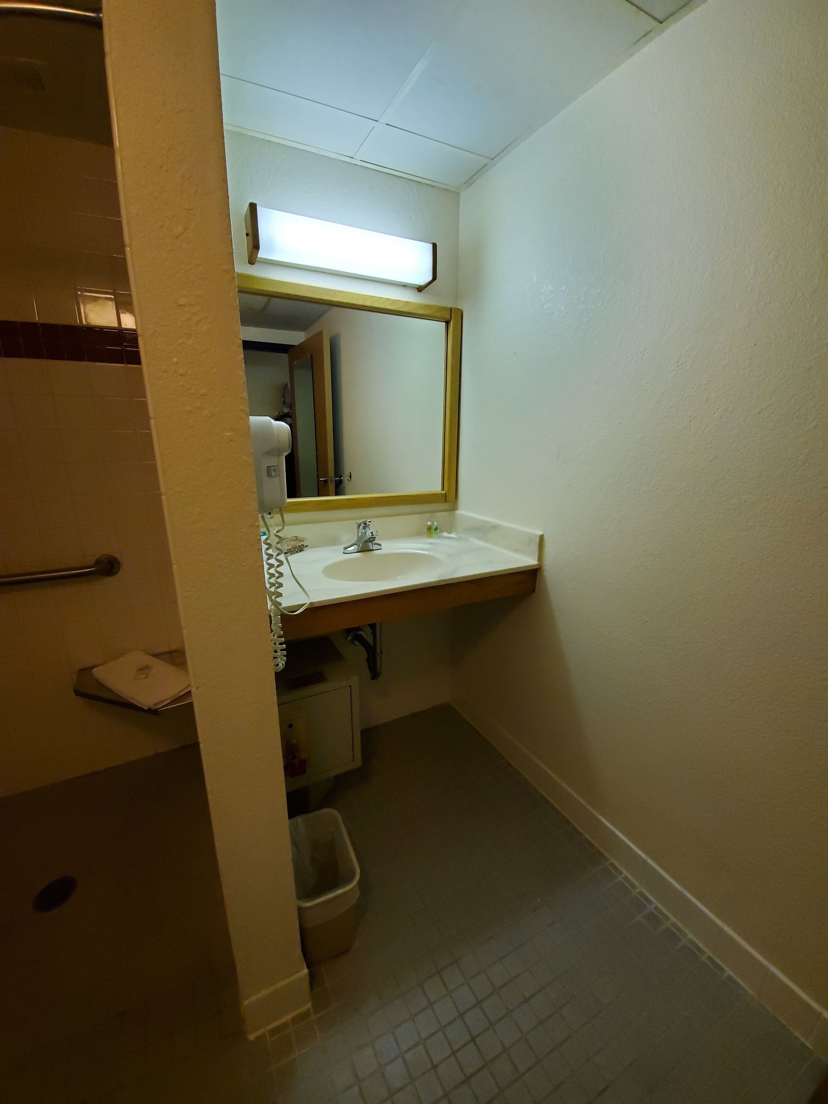 A small bathroom with a white sink, a mirror, and a towel rack.