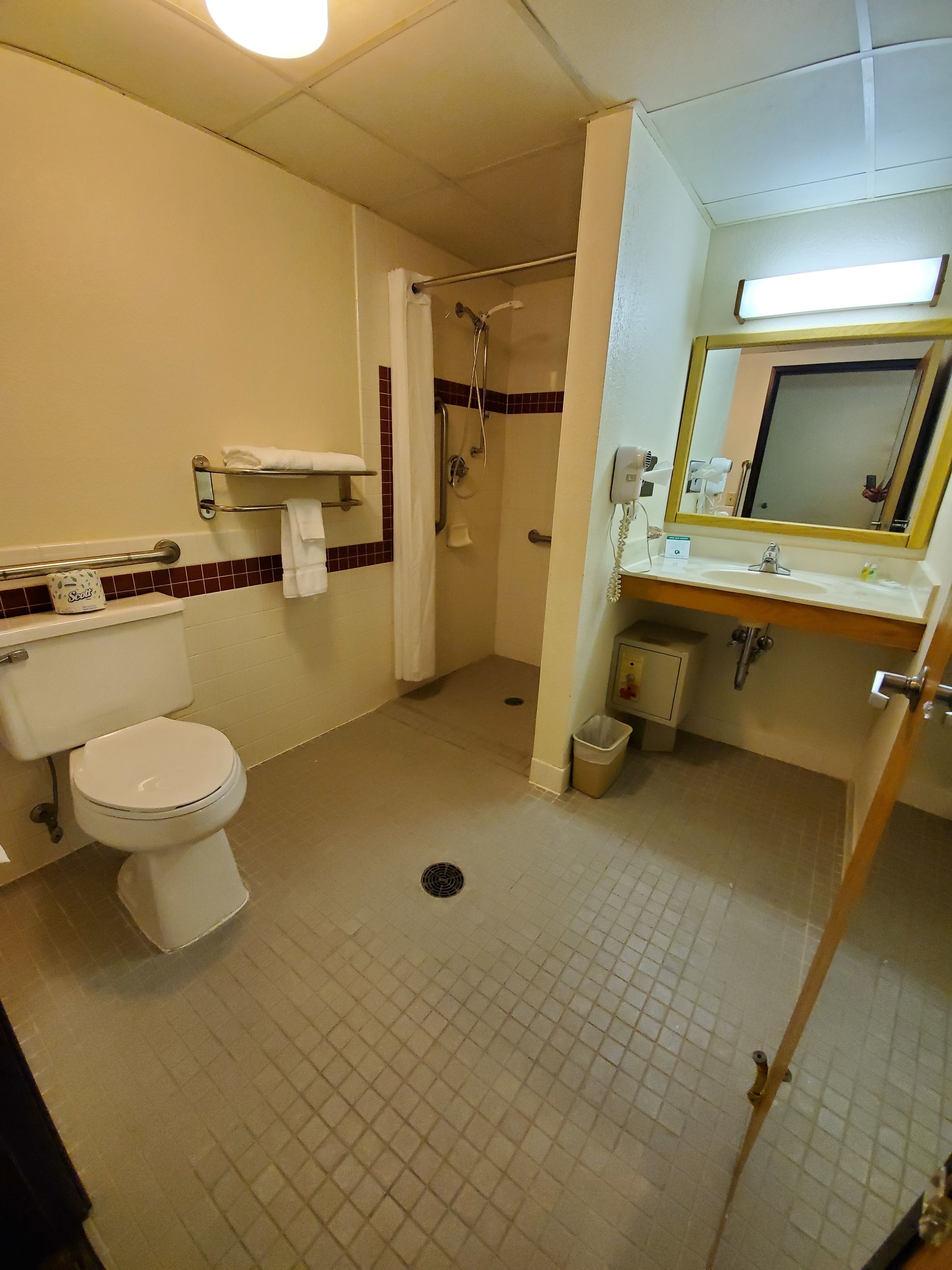 A standard hotel bathroom with a toilet, shower, and sink.