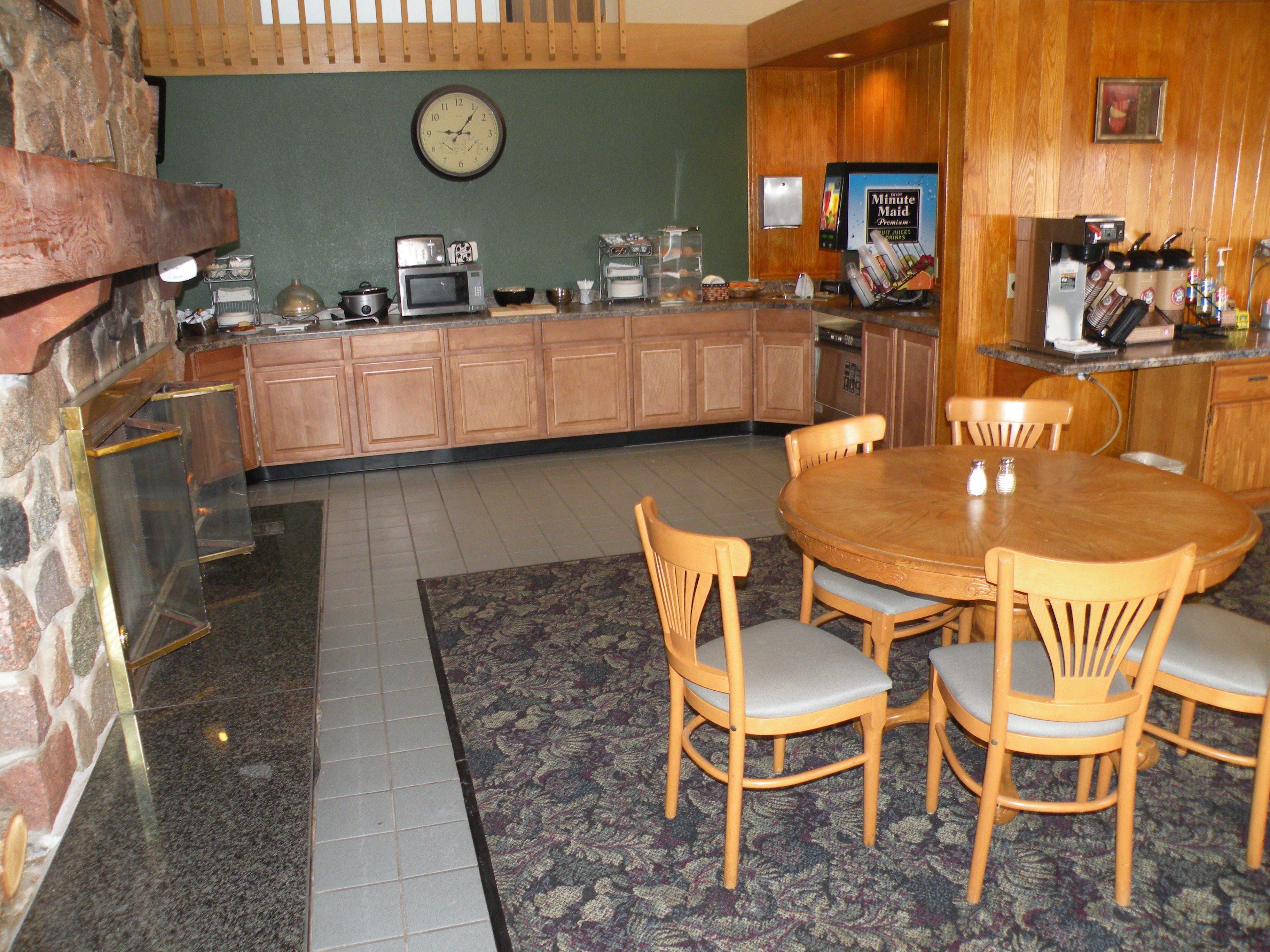 A kitchen with wooden cabinets, a microwave, a coffee machine, and a clock on the wall.