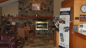 A lobby with a stone fireplace, seating area, and a reception desk with a sign about rewards. - Boarders Inn & Suites by Cobblestone Hotels - Ripon (Ripon)