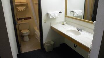 A small bathroom with a toilet, sink, and mirror. There is a towel rack above the sink and a trash bin next to it.