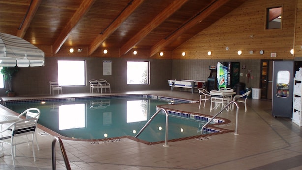 An indoor swimming pool with a no diving sign, surrounded by chairs and tables, and a wooden ceiling. - Boarders Inn & Suites by Cobblestone Hotels - Ripon (Ripon)