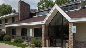 A two-story building with a brick facade, large windows, and a ramp leading to the entrance. There are signs indicating handicap parking and a reception area. - Boarders Inn & Suites by Cobblestone Hotels - Ripon (Ripon)