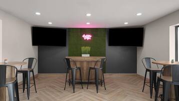 Un interior moderno con una zona de bar, dos televisores montados en la pared y un suelo de madera con diseño de espiga.