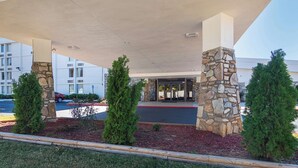 A hotel entrance with stone pillars, a covered walkway, and a parking lot. - Motel 6 Decatur, GA (Decatur)