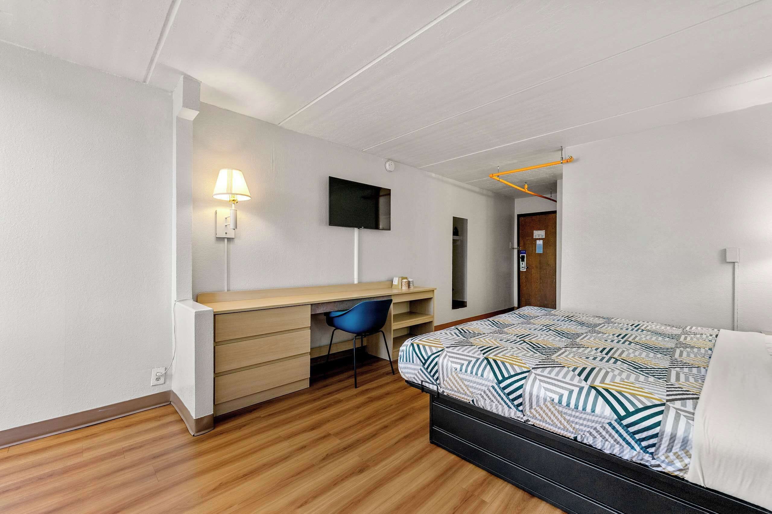 A bedroom with a bed, a desk, a chair, a TV, and a wardrobe.