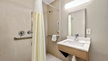 A modern bathroom with a shower, grab bars, a sink, and a mirror.