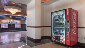 A hotel lobby with a Coca-Cola vending machine, a reception desk, and a chandelier. - Motel 6 Decatur, GA (Decatur)