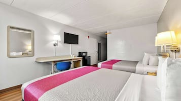 A hotel room with two beds, a desk, a chair, a TV, and a mirror.