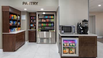 A pantry area with shelves stocked with snacks, beverages, and a coffee machine.