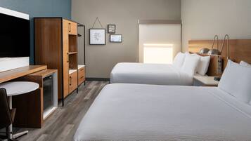 A hotel room with two beds, a desk with a chair, a television, and a wardrobe.