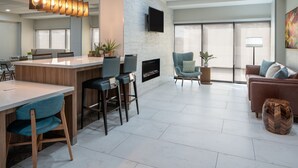 Uma sala de estar moderna com lareira, área de estar e cozinha com banquetas.