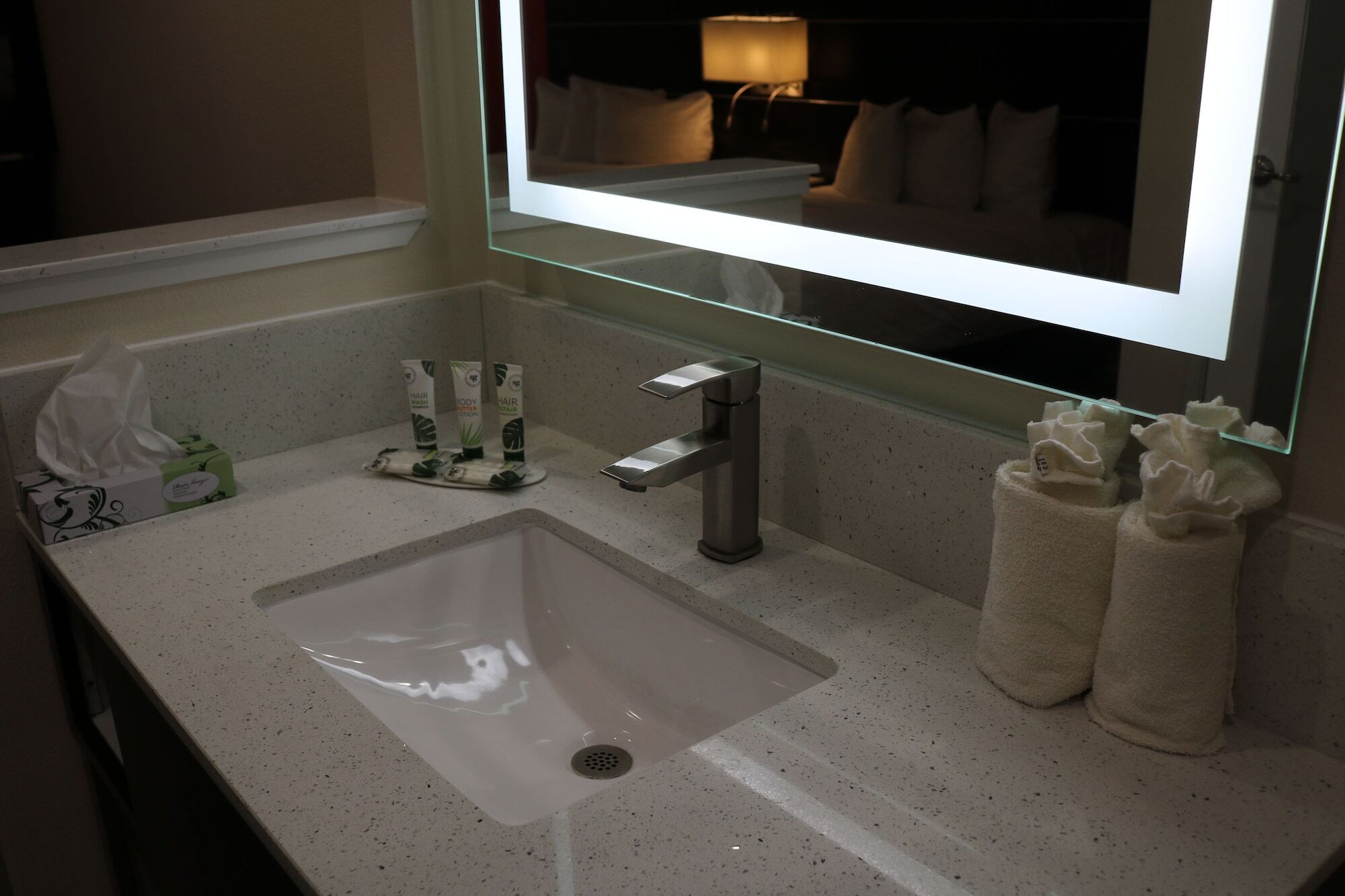 A bathroom with a sink, mirror, and toiletries.